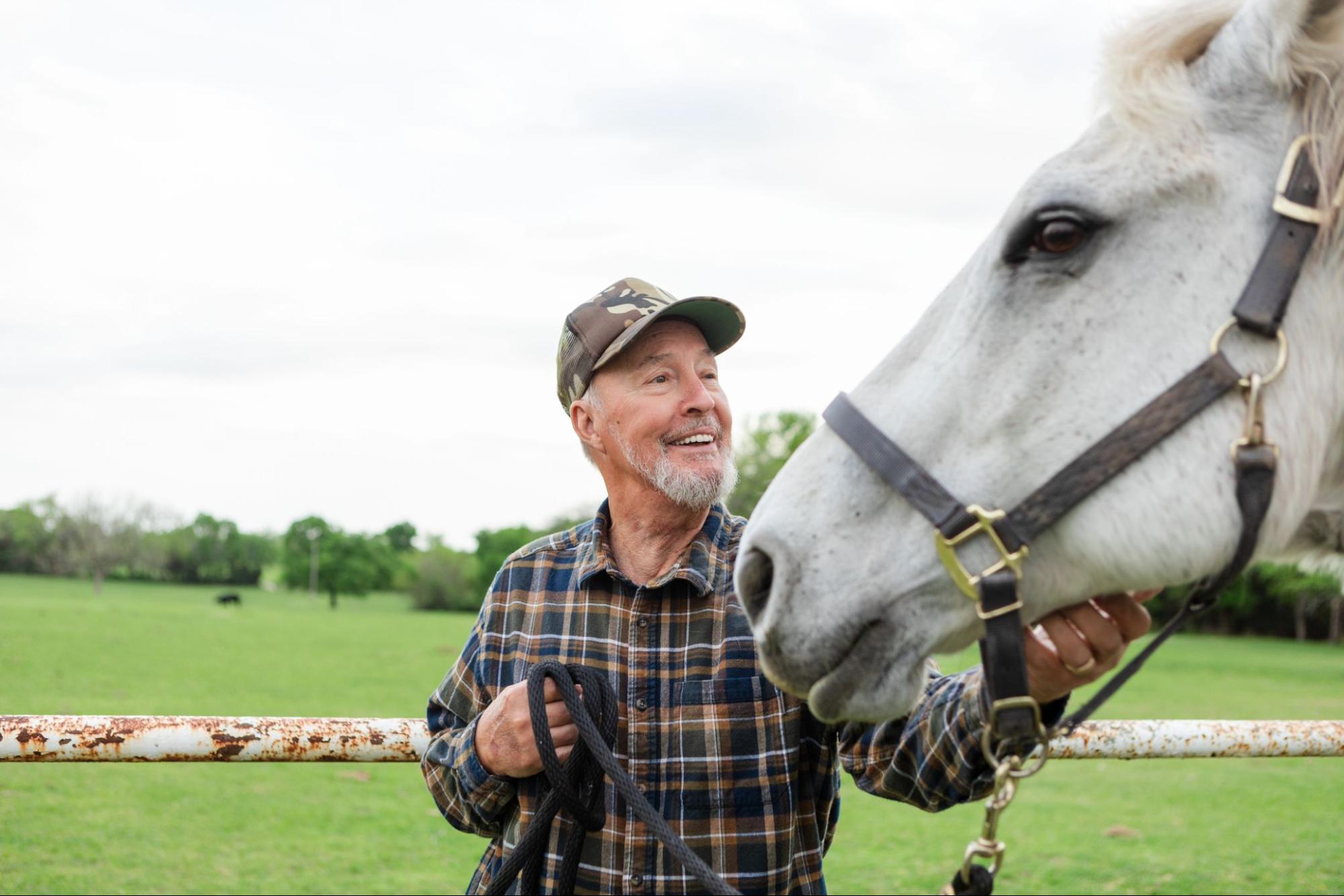 A smiling rancher with his white horse